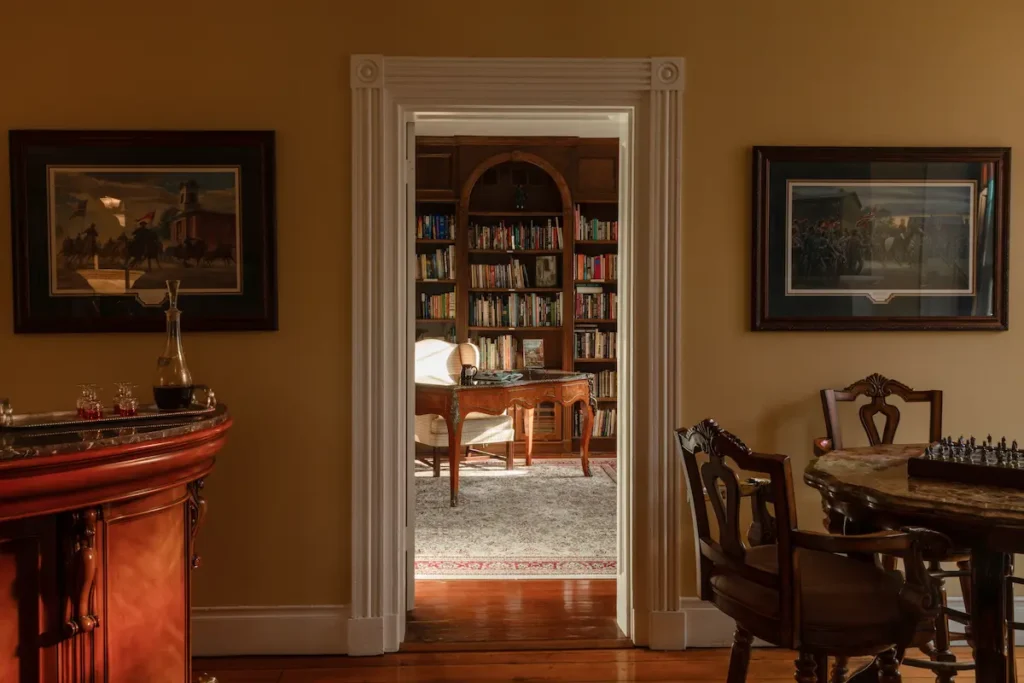 A doorway reveals a home office with bookshelves and a desk, flanked by rooms with dark furniture.